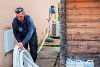 Poseur qui effectue la liaison d'une pompe à chaleur air / eau à l'extérieur d'une maison