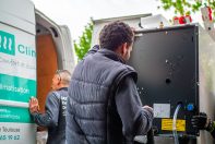 Un poseur qui transporte une PAC air / eau vers une maison. Un autre poseur est derrière le camion ClimeHome