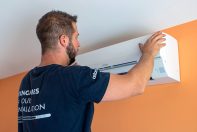 Technicien ClimeHome en train de finaliser l'installation d'un climatiseur sur le mur orange d'une maison individuelle