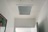 Grille de soufflage sur le plafond d'un couloir avec des peintures entièrement peints en blanc