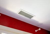 Grille de soufflage installée près de la fenêtre d'une maison aux murs rouge